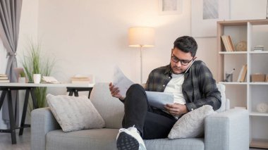 İş görüşmesi. Başlangıç tartışması. Mobil iletişim. Ciddi meşgul bir çalışan telefonda konuşuyor. Ofisteki kanepede istatistik analizi yapıyor..