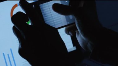 Ofis sahtekarı. Veri hırsızlığı. İşyeri bilgisayarında gece geç saatlerde akıllı telefondan kurumsal gizli proje bilgi istatistiklerinin fotoğrafını çeken adam elleri.
