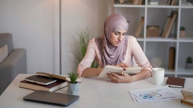 Kitap araştırması. İş eğitimi. Dahi konsantre genç kadın stajyer ev ofis iş yerindeki öğrenim hesabı kursunu okuyor..