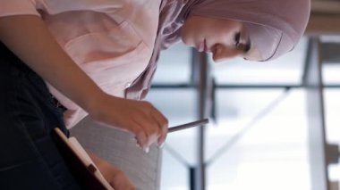 Dikey video. Günlük boş zaman. Hobi yazıyorum. Hafta sonu evde. Düşünceli, ilham verici kadın öğrenci rahat koltukta günlük planlaması yapıyor..