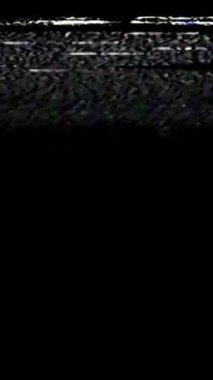Dikey video. Analog hatası. Televizyon tahılları. Ekran bozulması. Beyaz gerçek statik gürültü objeleri koyu siyah soyut serbest alan arkaplanı üzerinde doku hareketi.