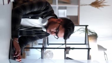 Dikey video. Uzaktan eğitim. Ev ödevi. Mesafe öğrenme. Bilgisayarda daktilo kullanan ciddi odaklı bir adam. Masa başı işyerinde ödev üniversitesi araştırması yapıyor..