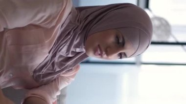 Dikey video. Sanal konuşma. Telefon iletişimi. Hücre eğlencesi. Neşeli, güzel bir kadın evdeki kanepede sosyal medyada konuşuyor..