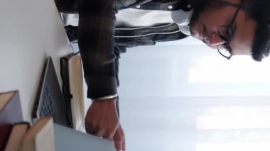 Dikey video. Hesap yöneticisi. Veri kontrolü. Başlangıç projesi. Ciddi bir adam iş pazarlama belgelerini analiz ediyor istatistik yazıyor ev bilgisayarında kahve içiyor..