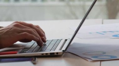 İş casusluğu. Bilgi hırsızlığı. Dolandırıcı adamın elleri dizüstü bilgisayarda yazı yazarken ofis masasında çalışan bir kadınla gizli bilgilerin fotoğrafını çekiyor..