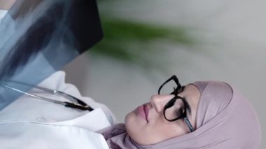 Dikey video. Radyoloji ilacı. Röntgen incelemesi. Klinik teşhisler. Ciddi profesyonel kadın pratisyen doktor hastanede akciğer zatürresi taraması yapıyor..