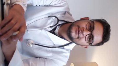 Dikey video. Sanal doktor. Çevrimiçi sağlık hizmeti. Teletıp danışmanlığı. Pratisyen adam hastane işyerindeki internet görüşmesinde teşhis hakkında konuşuyor..