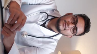 Dikey video. İlaç reçetesi. Antibiyotik tedavisi. Doktor tavsiyesi. Erkek doktor klinikteki internet aramasında haplardan bahsediyor..