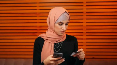 Cep telefonu ödemesi. İnternet alışverişi. Kafe 'de kredi kartı para transferi yapan tesettürlü çekici bir kadın telefon bankacılığı uygulamasından internetten sipariş veriyor..