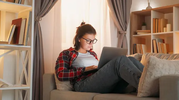 ホーム ワーク フリーランスの仕事 インターネットレジャー 集中した女性従業員は オンライン座っているソファルームのインテリアにノートパソコンのブラウジングを入力します — ストック写真
