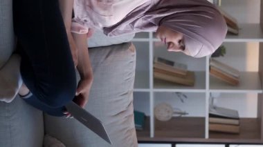 Dikey video. İnternet taraması. Uzaktan kumanda. Sakin kadın serbest sörf yapıyor. Ev oturma odasındaki rahat kanepede dizüstü bilgisayarla yazı yazıyor..