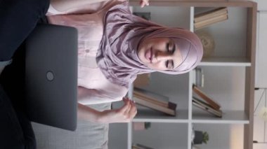 Dikey video. Uzaktan sohbet. İnternet araması. Laptop iletişimi. Oturma odasının iç tarafındaki rahat koltukta sanal bir toplantıda konuşan bir kadın..