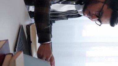 Dikey video. Hesap yöneticisi. Veri kontrolü. Başlangıç projesi. Ciddi bir adam iş pazarlama belgelerini analiz ediyor istatistik yazıyor ev bilgisayarında kahve içiyor..