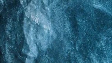 Işıltılı girdap. Suyu boya. Kar fırıldağı. Parlak mavi renkli sis, koyu kaba dokuda yüzen parlak toz parçacıkları soyut sanat arkaplanı.