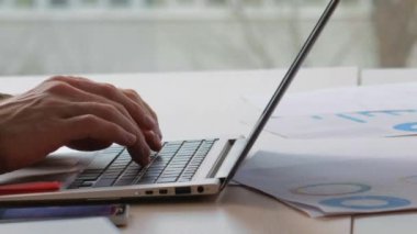 İş casusluğu. Bilgi hırsızlığı. Dolandırıcı adamın elleri dizüstü bilgisayarda yazı yazarken ofis masasında çalışan bir kadınla gizli bilgilerin fotoğrafını çekiyor..