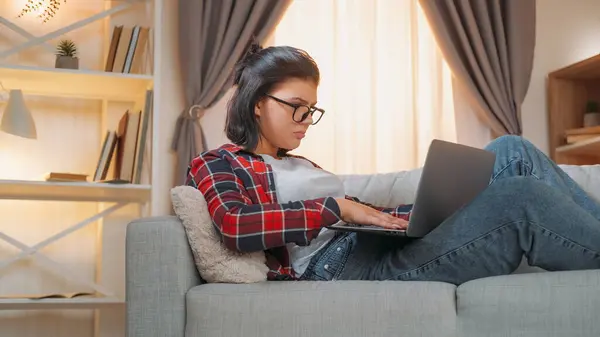 在线工作 数字技术 一个非常专注的女人坐在家里房间的沙发上打字 — 图库照片