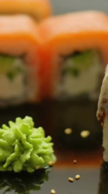 Dikey video. Suşi seti. Japon yemeği. İnsan eli yemek çubuklarıyla ekmek topluyor Asya restoranında lezzetli yemekler yiyor..