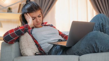 Uykulu kadın. İnternet bağımlılığı. İş yorgunluğu. Dizüstü bilgisayarla uyuyan aşırı çalışan serbest çalışan kadın kanepe odasında oturuyor..