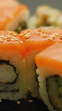 Dikey video. Somon suşisi. Japon mutfağı. Asya restoranının geleneksel yemeklerinde susamlı lezzetli ekmekler..