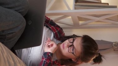 Dikey video. Uzaktan kumanda. Freelancer rutini. Ağ araştırması. Dizüstü bilgisayarın iç mekanında yoğun çalışan kadın sörf yapıyor..