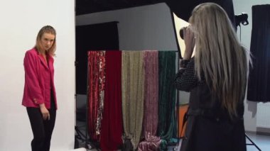 Sahne arkası modası. Model fotoğrafçılık. Fotoğraf çeken profesyonel stüdyo çalışanı bir kadın kameraya poz veriyor..