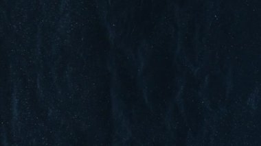 Parlak toz dokusu koyu arkaplan. Gece gökyüzü. Yıldız tozu parıldıyor. Düz olmayan soyut sanat yüzeyinde yüzen parlak yıldız parçacıkları.