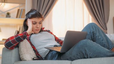 Sıkıcı kadın. Online eğitim. Yorgunluğa çalış. Kanepe odasında uykulu görünümlü dizüstü bilgisayar hisseden yorgun bir kız öğrenci..