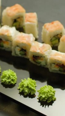 Dikey video. Suşi seti. Yuvarlanıp yiyor. İnsan eli Asya yemeği topluyor Japon mutfağı lezzetli lezzetli yemekler restoranda.
