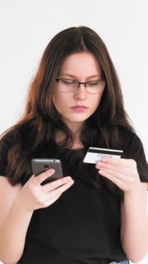 Dikey video. İnternetten alışveriş. Mobil bankacılık. İnternet ödeme işlemleri için CVV kodlu kredi kartı bilgilerini kullanan kendine güvenen bir kadın beyazdan izole edilmiş.