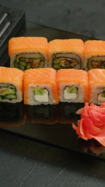 Dikey video. Suşi seti. Yuvarlak çeşitleri. Lokantada geleneksel Asya mutfağı Japon yemekleri, karanlık arka planda..