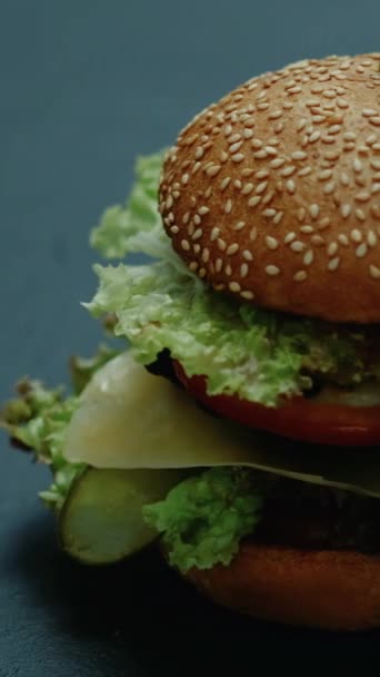垂直录像 不健康的汉堡快餐 美味的汉堡包美国烹调垃圾营养芝士汉堡在深色背景下被分离出来 — 图库视频影像