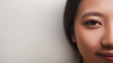 Yarı yüz güzellik. Dişi cilt bakımı. Reklam arkaplanı. Çıplak makyajlı, beyaz fotokopi odası pozu veren sakin, mutlu kadın..