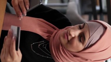 Dikey video. Mobil alışveriş. Dijital ödeme. Keyifli bir kadın internet üzerinden alışveriş yapıyor. Akıllı telefonlu internet mağazasından. Telefon bankacılığı kafede oturuyor..