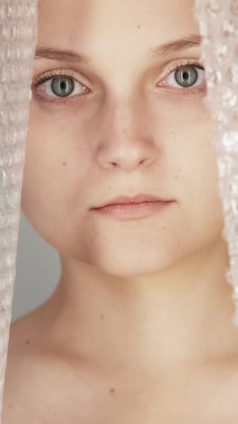 バーティカルビデオ 女性虐待 家庭内暴力 Upset 傷ついた怖い絶望的な女性の犠牲者の顔の肖像画プラスチック バブルのラップのフィルム カーテン — ストック動画