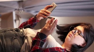 Dikey video. Telefon siparişi. Alışveriş çağrısı. Banka servisi. Akıllı telefondan ev ışığı içerisinden kredi kartıyla alışveriş yapan sıradan bir kadın..