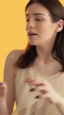 Dikey video. Tatil indirimi. Alışveriş yarışları. Satın alma bağımlılığı. İstenilen çantaları turuncu arka planda tutamayan kadın..