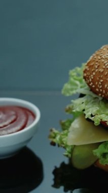 Dikey video. Fast food restoranı. Önemsiz bir yemek. Hamburger, patates kızartması ve domates sosu ketçap..