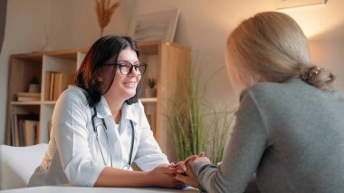 Destekleyici doktor. Sağlık kontrolü için. Profesyonel sağlık hizmeti. Dost canlısı kadın pratisyen doktor hastane odasında kadın hastanın elini tutuyor..