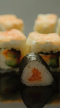 Dikey video. Rolls servis. Maki suşisi. Yemek stilisti el Japon yemeklerini sıra sıra deniz ürünlerine sardı. Restoranda Asya mutfağı..