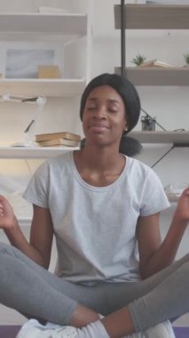 Dikey video. En sevdiğin şarkı. Egzersiz müziği. Keyfin yerinde. Mutlu, genç, kaygısız bir kadın evde yoga yaptıktan sonra ritim tutarak dans ediyor ve şarkı listesinin keyfini çıkarıyor..