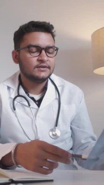 Dikey video. Doktor randevusu. Tıbbi tavsiye. Steteskoplu bir doktor hastane işyerindeki akciğer röntgeni hastalığında danışmanlık yapıyor..