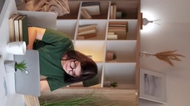 Dikey video. Kadın işkolik. Uzaktan serbest çalışan. İnternet araştırması. Yoğun çalışan bayan çalışanlar ev bilgisayarın ışık odası iç tarafında öğreniyor..