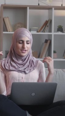 Dikey video. Uzaktan sohbet. İnternet araması. Laptop iletişimi. Oturma odasının iç tarafındaki rahat koltukta sanal bir toplantıda konuşan bir kadın..