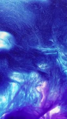 Dikey video. Parlak sıvı sıçraması. Su karışımı boya. Mavi mor pembe renkli ışıldayan parçacıklar desen mürekkep damlası hareket soyut sanat arkaplanı.