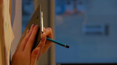 Dikey video. Şirket evrakları. İş projesi. Ofisteki kadın, akşam işyerinde istatistik belgelerini inceleyen pano kontrol listesine yazı yazarken ellerini uzattı.