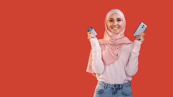 Mobile Banking Online Shopping Zufriedene Fröhliche Frau Hijab Zeigt Kreditkartentelefon lizenzfreie Stockfotos