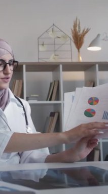 Dikey video. Tıbbi çizelgeler. Sağlık sigortası. Ciddi kadın doktor hastanedeki Webinar çağrı toplantısında istatistik grafiklerini tartışıyor..