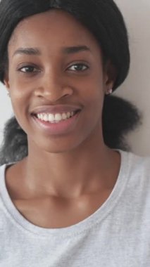 Dikey video. Kadın mutluluğu. Pozitif portre. Neşeli, kaygısız, mutlu, güzel bir kadın yüzü beyaz arka planda güzel dişli bir gülümsemesi var..