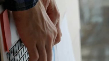 Dikey video. İnternette çalışıyorum. Bilgisayar projesi. İş adamı, çalışma masasındaki kurumsal görevleri tamamlamak için dizüstü bilgisayarda klavye kullanıyor..