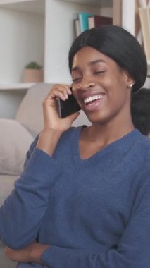 Dikey video. Telefon var. Mobil konuşma. Gadget iletişimi. Mutlu kadın akıllı telefonda sohbet ediyor 5G bağlantının keyfini çıkarıyor rahat bir oturma odasında yerde dinleniyor..